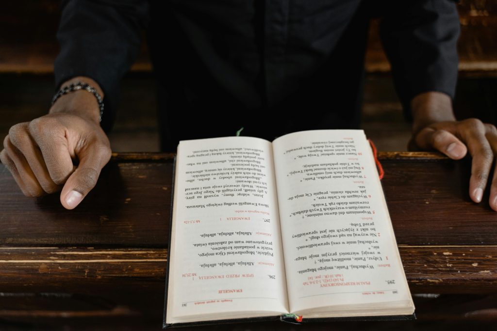 pexels photo 7219006 7219006 A close-up view of a priest reading an open bible during a church service, focus on hands and book.